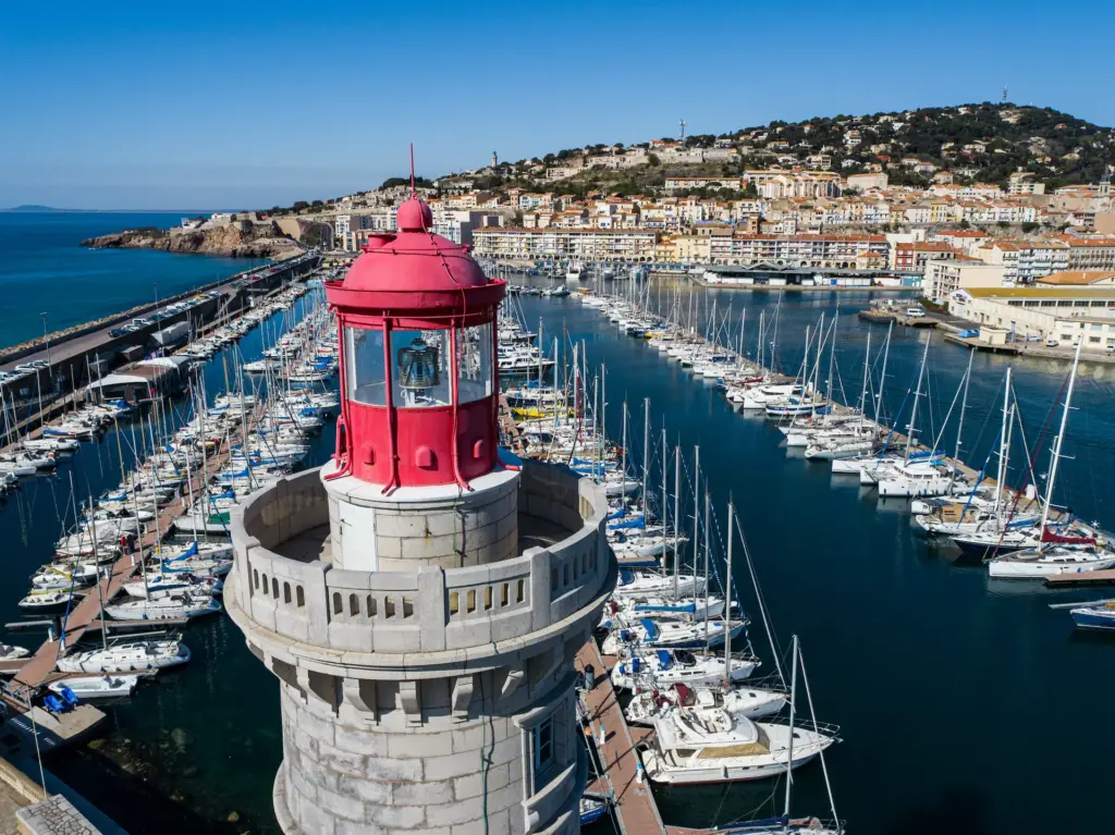 Phare rouge et port avec bateaux à quai.