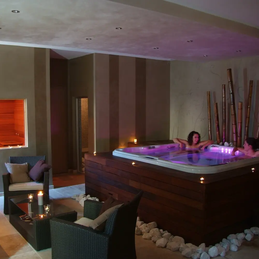 Spa intérieur avec jacuzzi et bougies allumées.