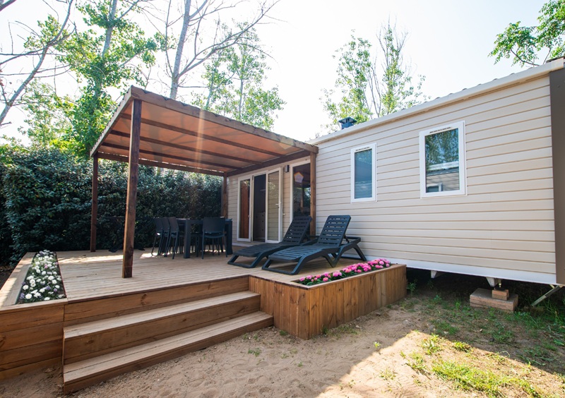Mobil-home avec terrasse en bois et transats.