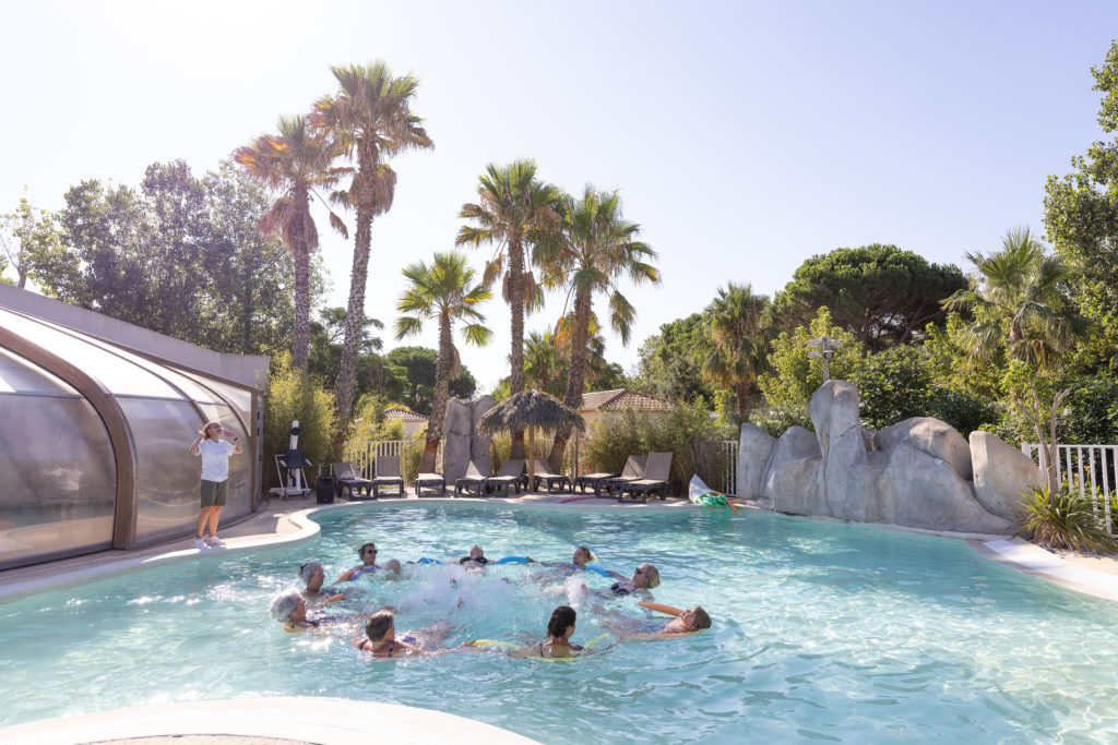 Groupe nageant dans une piscine extérieure ensoleillée.