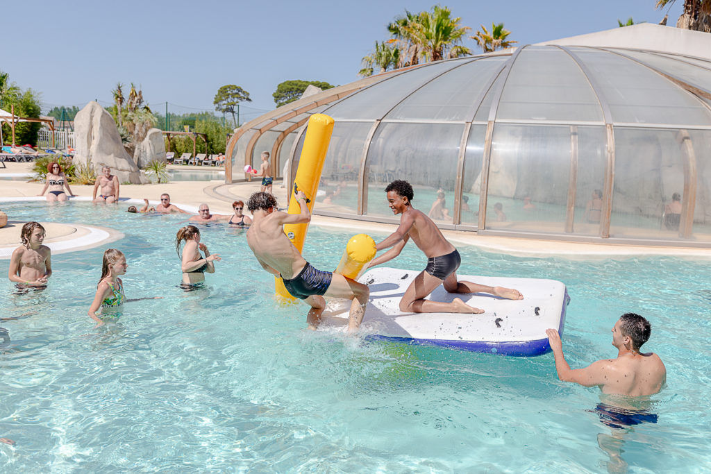 Bataille de bouées dans une piscine extérieure animée.