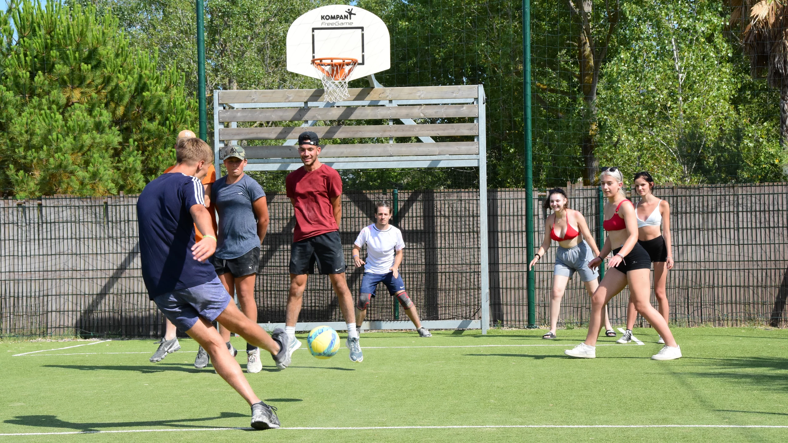 Jeunes jouent au foot sur terrain gazonné.