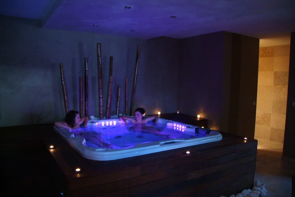 Deux personnes se relaxent dans un jacuzzi éclairé.
