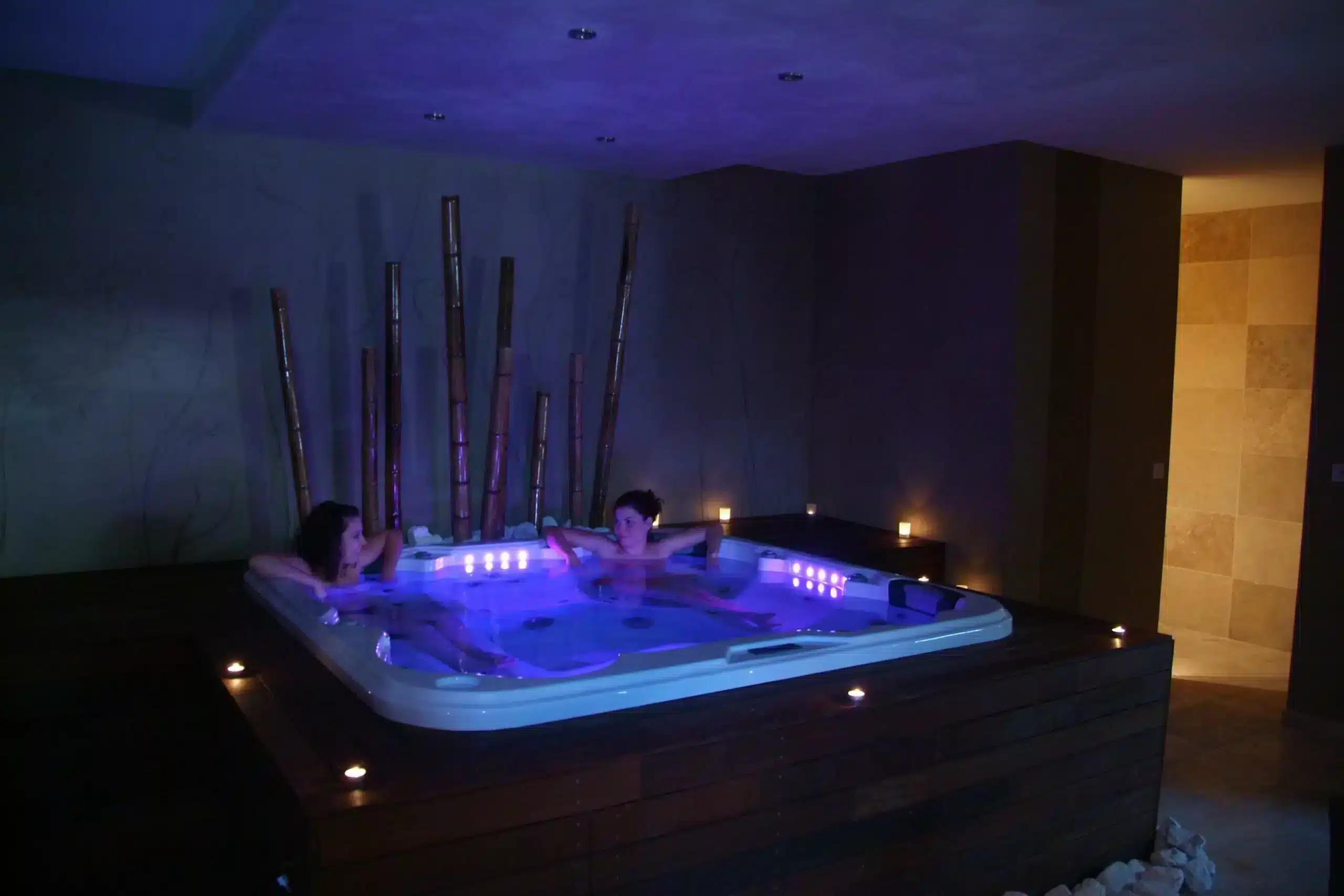 Deux personnes se relaxent dans un jacuzzi éclairé.