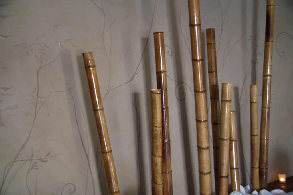 Tiges de bambou devant mur décoratif.