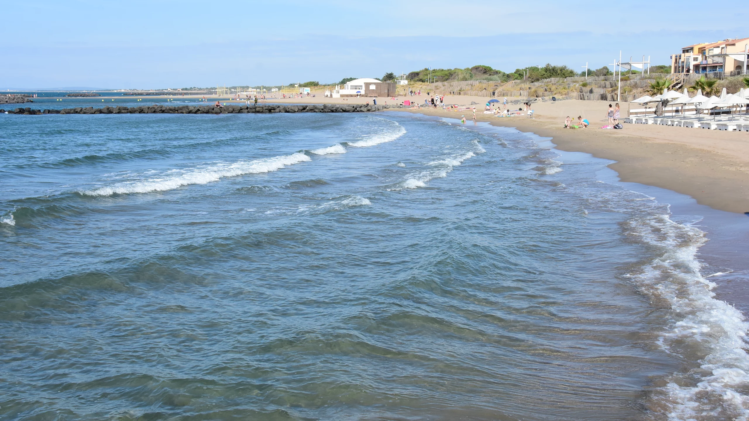 Plage avec vagues et sable sous ciel bleu.