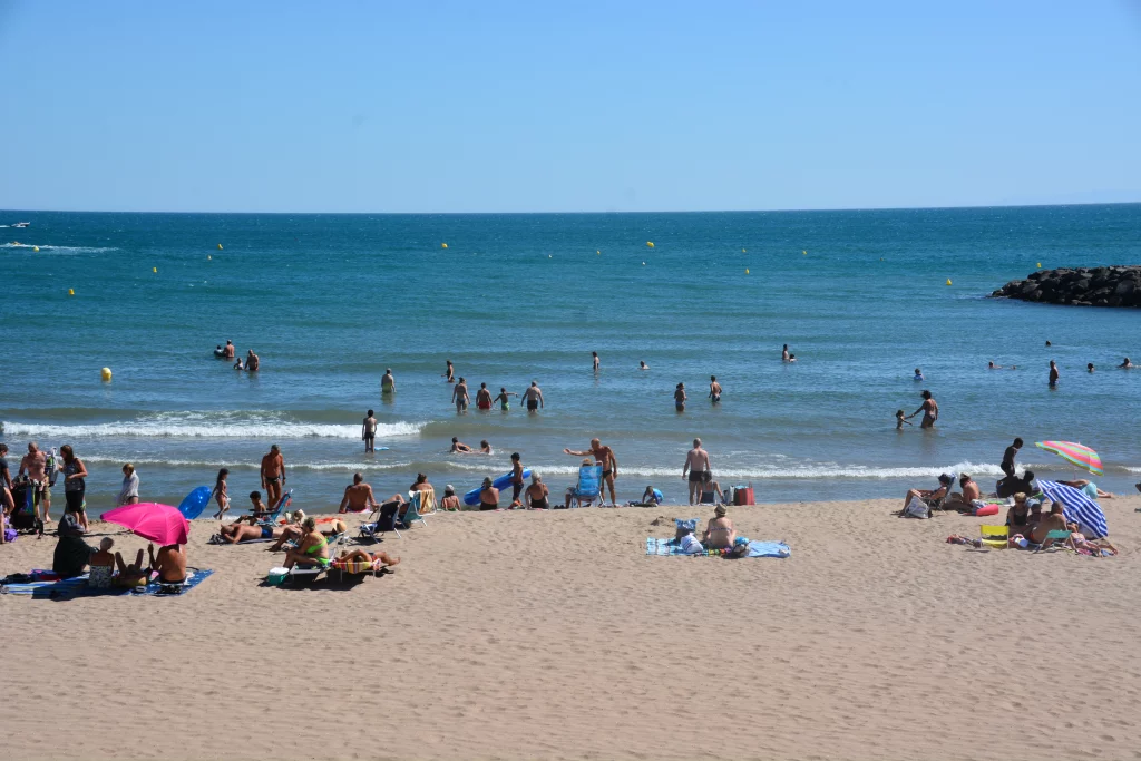Plage avec baigneurs et parasols colorés.