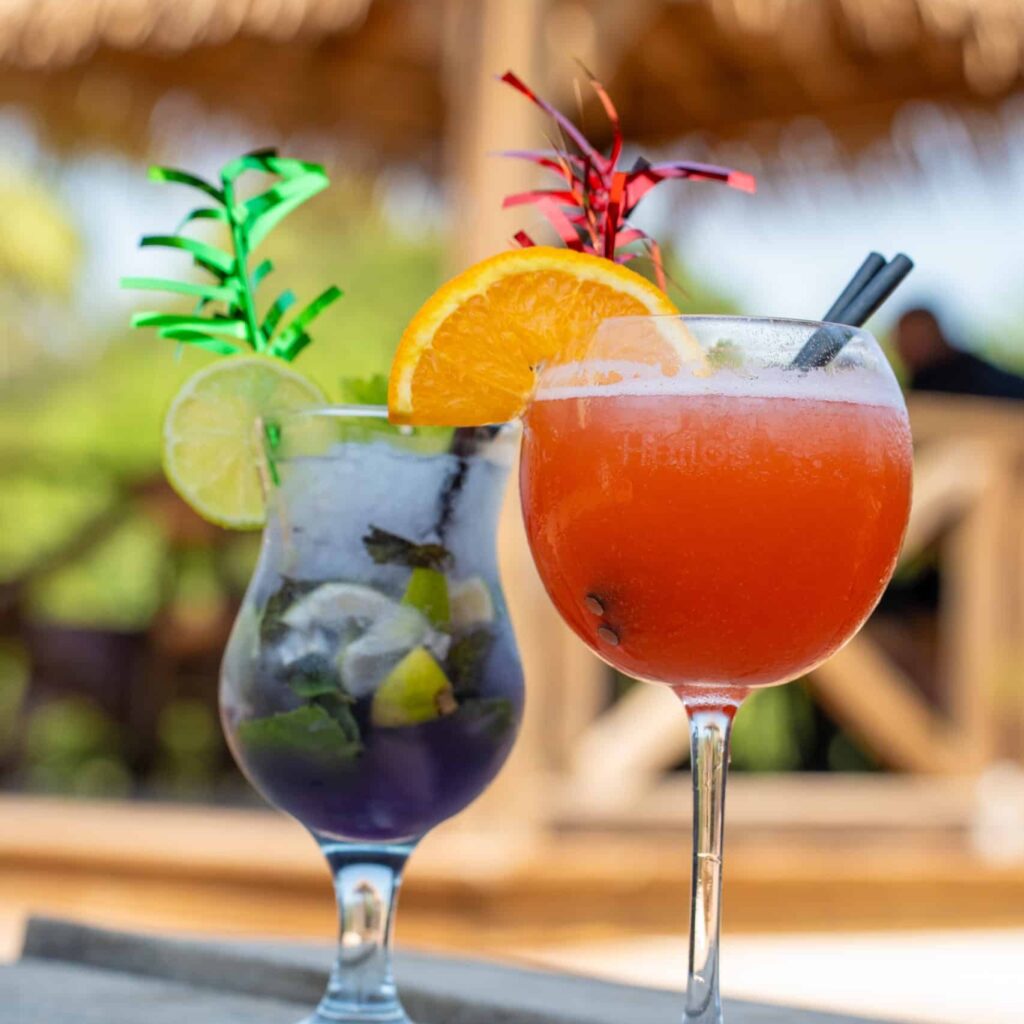 Zwei farbenfrohe Cocktails auf einem Tisch im Freien.
