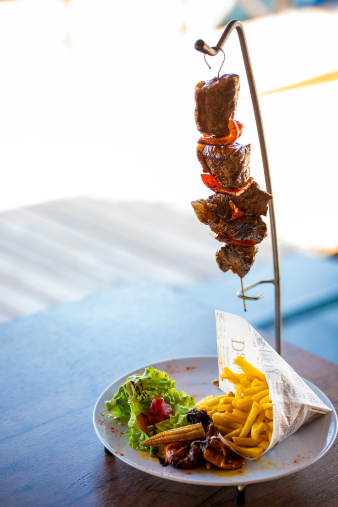 Brochette de viande et frites sur assiette.