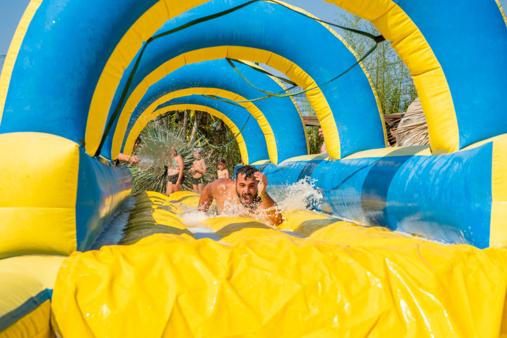 Homme glissant sur un toboggan aquatique gonflable.