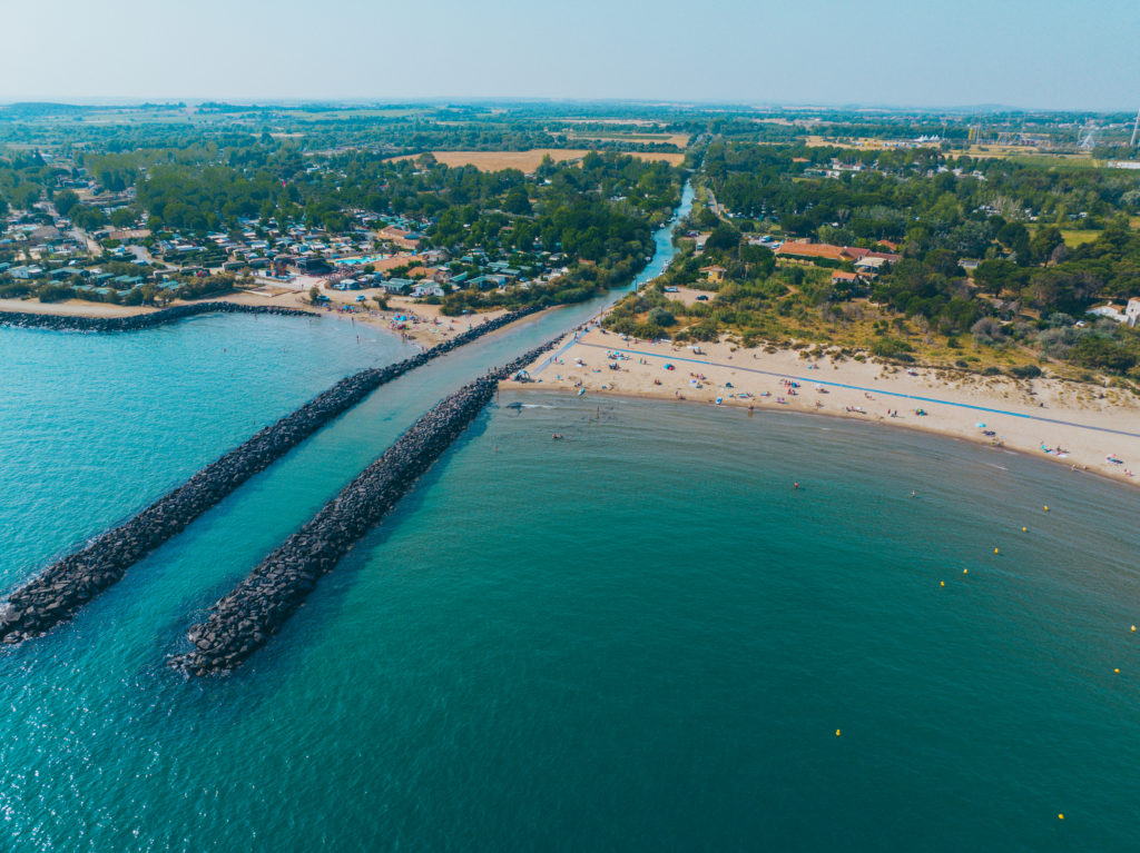 Vue aérienne de plage et digues rocheuses.