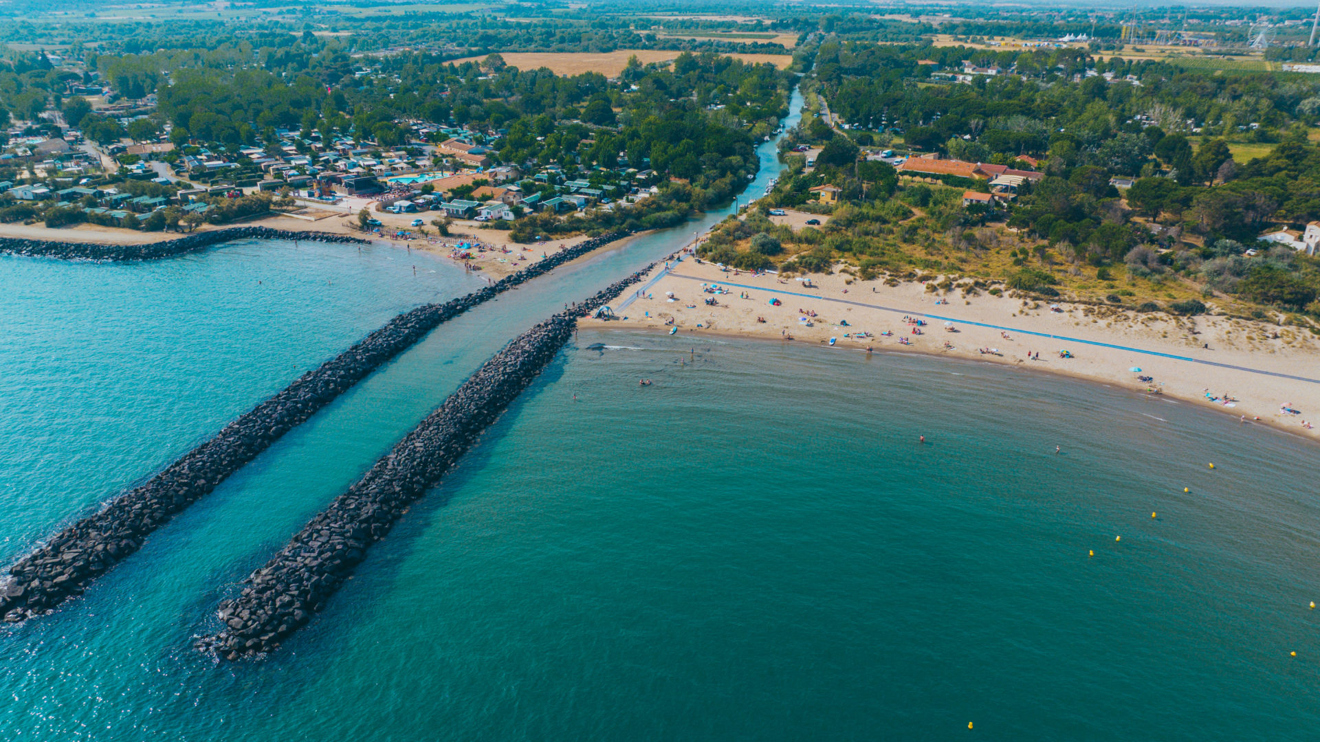 Vue aérienne plage et digue rocheuse.