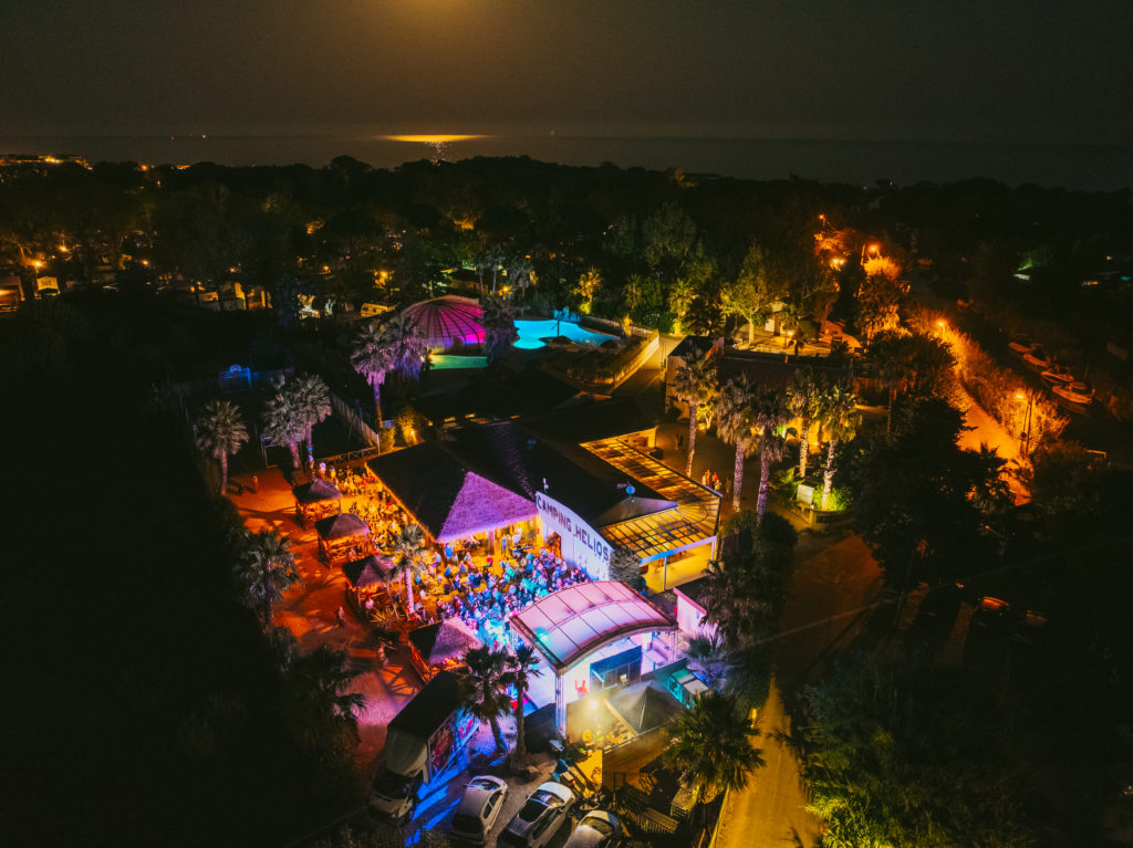 Vue aérienne nocturne d'un camping lumineux.