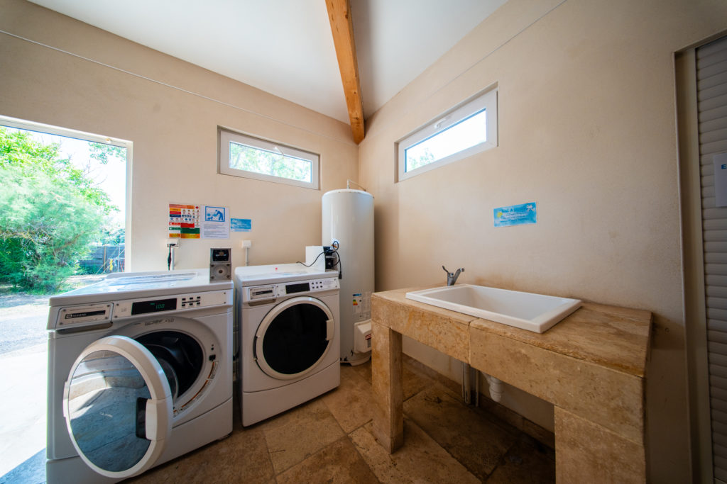 Buanderie avec machine à laver et évier en pierre.