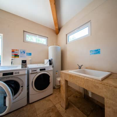 Buanderie avec machine à laver et évier en pierre.