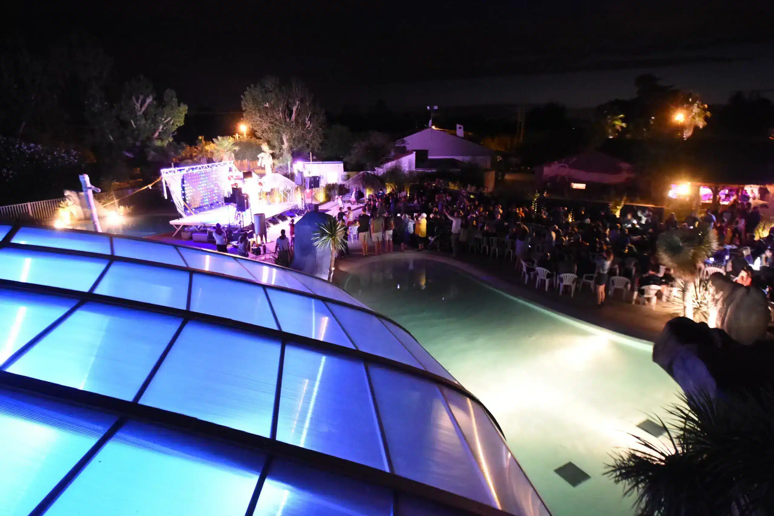 Concert nocturne près d'une piscine éclairée.