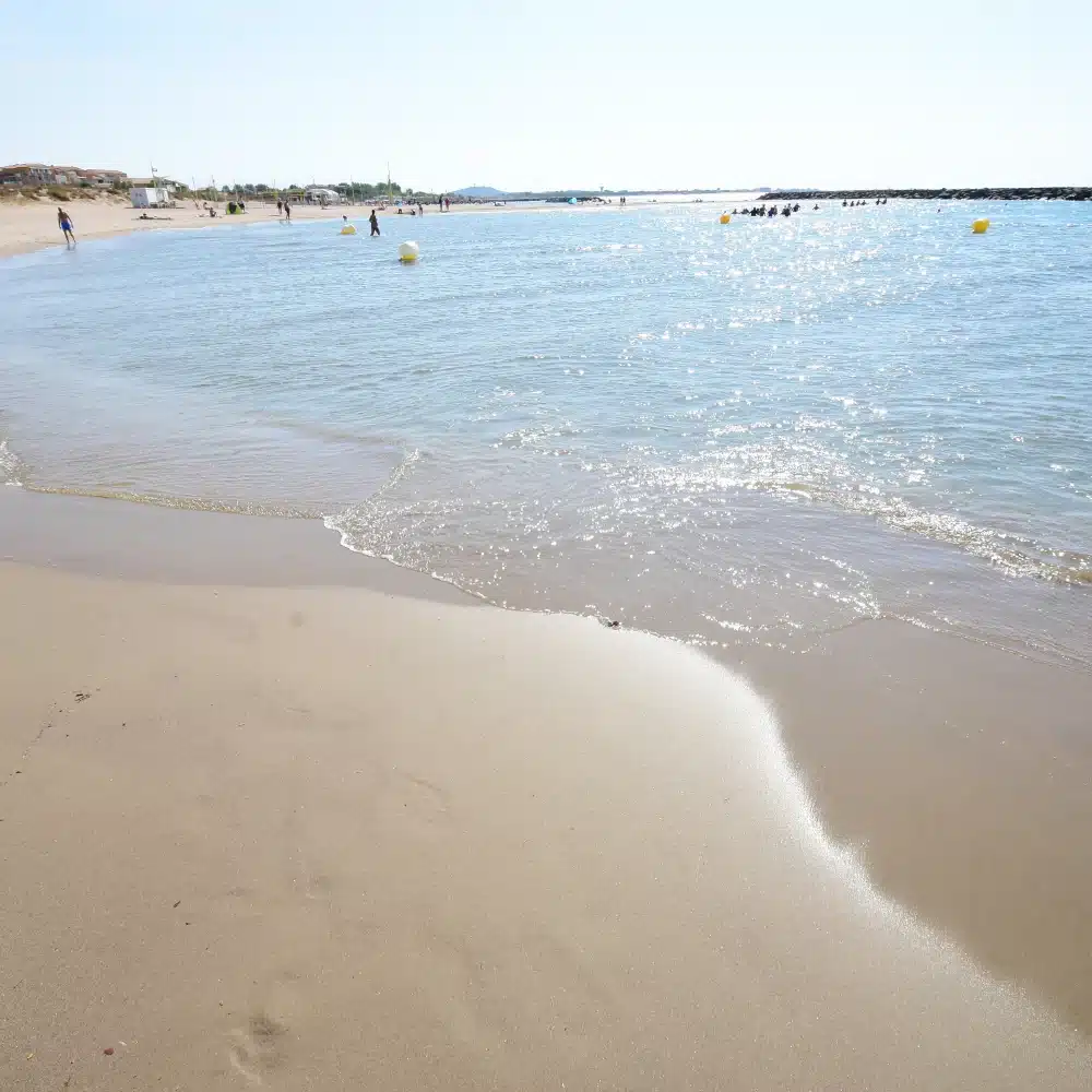 Plage de sable avec mer calme sous le soleil.