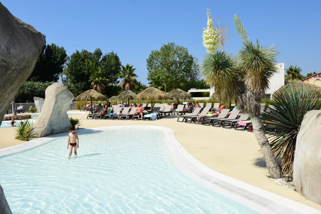 Piscine extérieure avec transats et parasols.