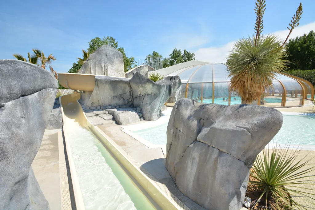 Piscine avec toboggan et dôme couvert.