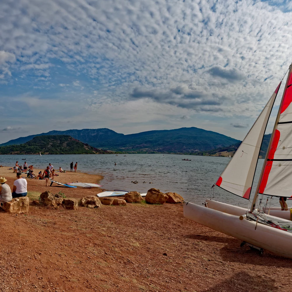 Plage avec voilier et montagnes en arrière-plan