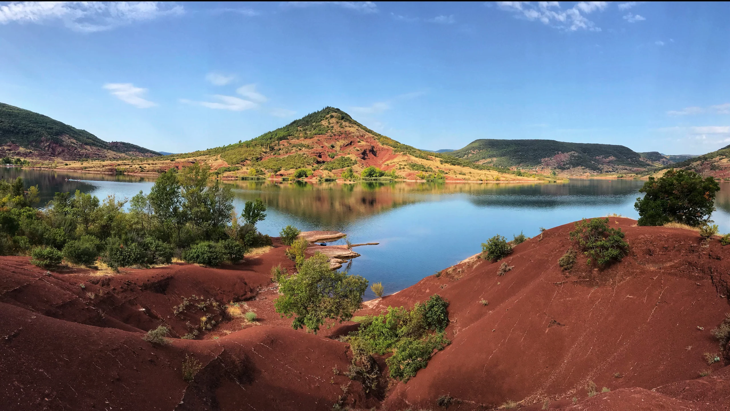 Paysage lac volcanique avec collines rouges.