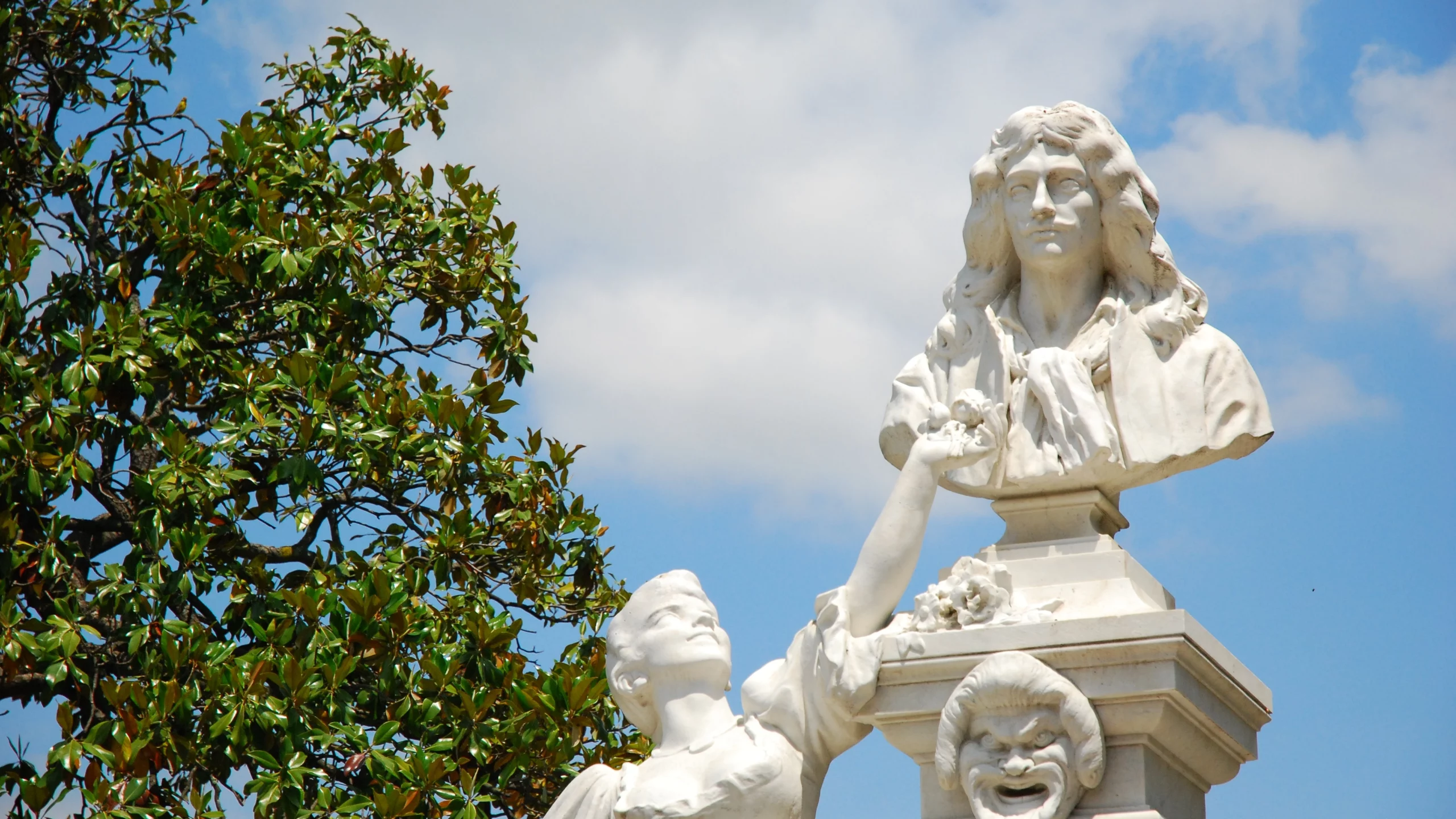 Statue en marbre avec arbre et ciel bleu.