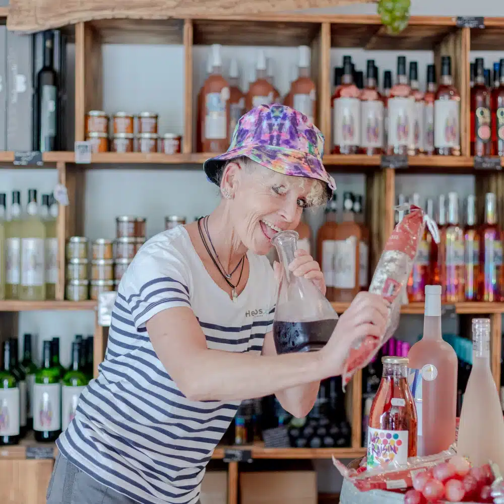 Femme déguste produit local dans cave à vin.