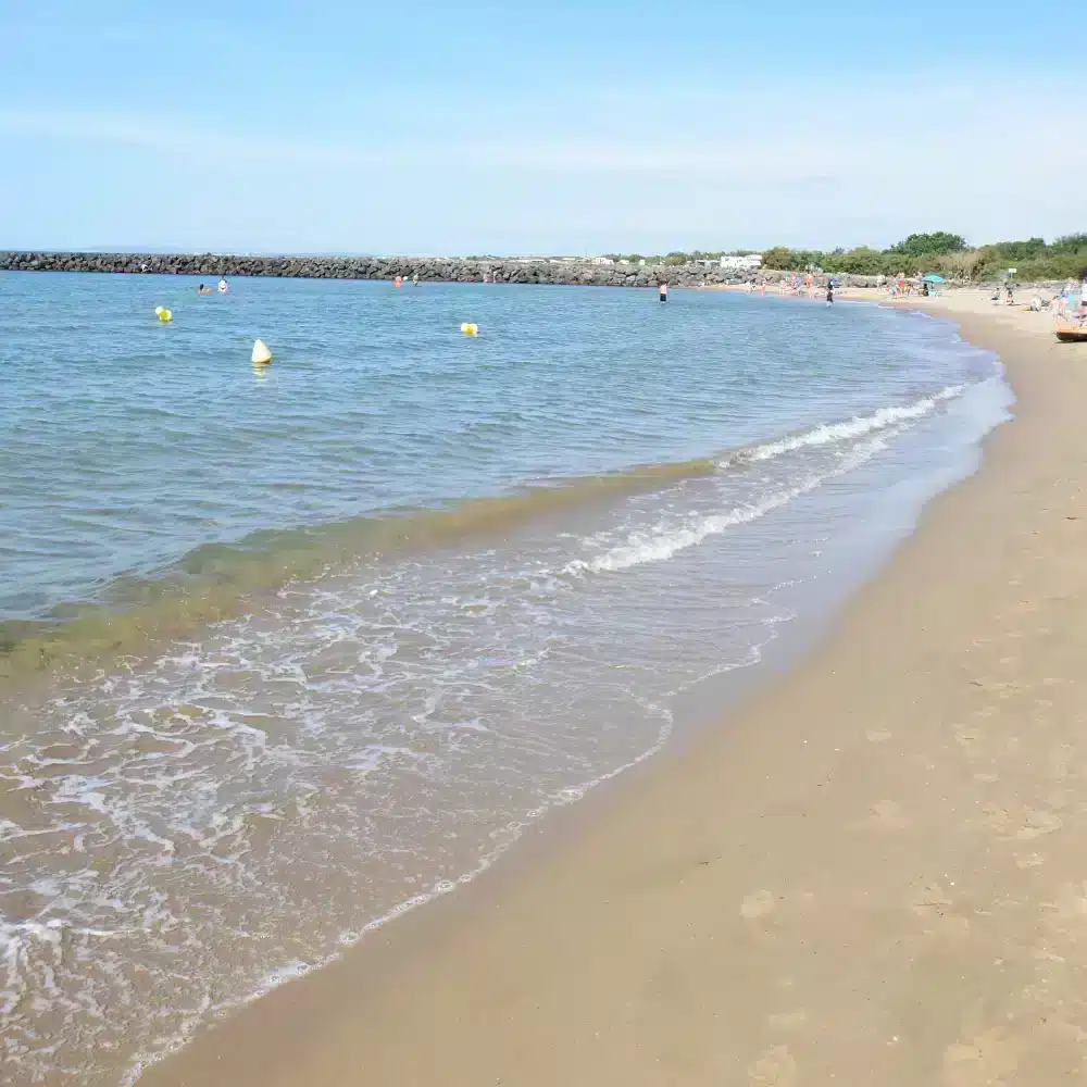 Plage sablonneuse avec quelques baigneurs.
