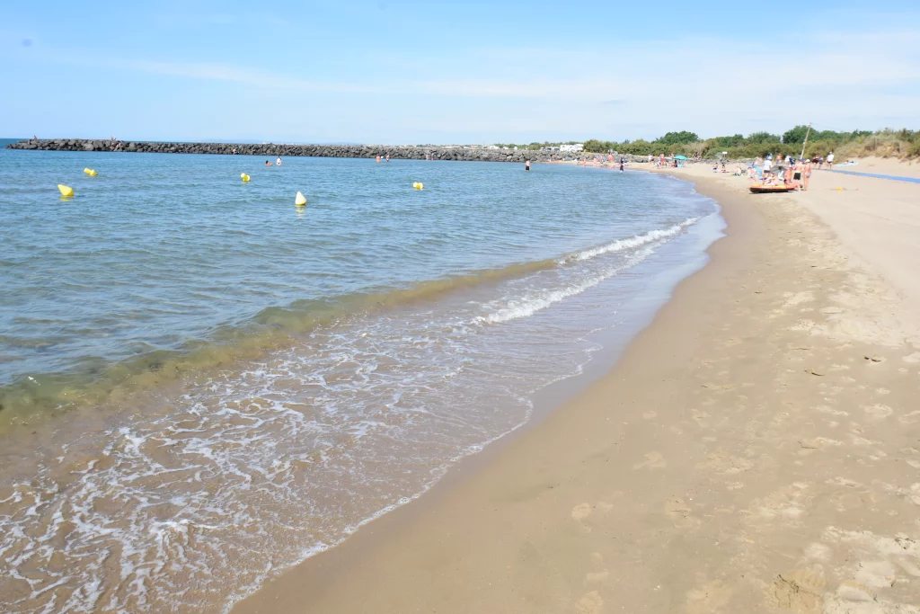 Plage sablonneuse avec quelques baigneurs.