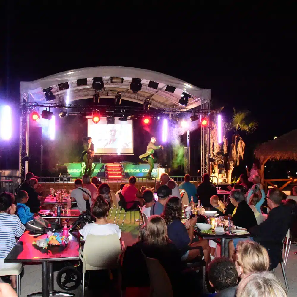 Spectacle de nuit avec public et scène éclairée.