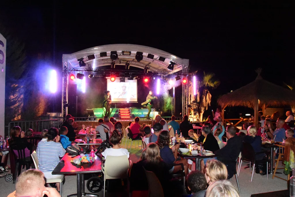 Spectacle de nuit avec public et scène éclairée.