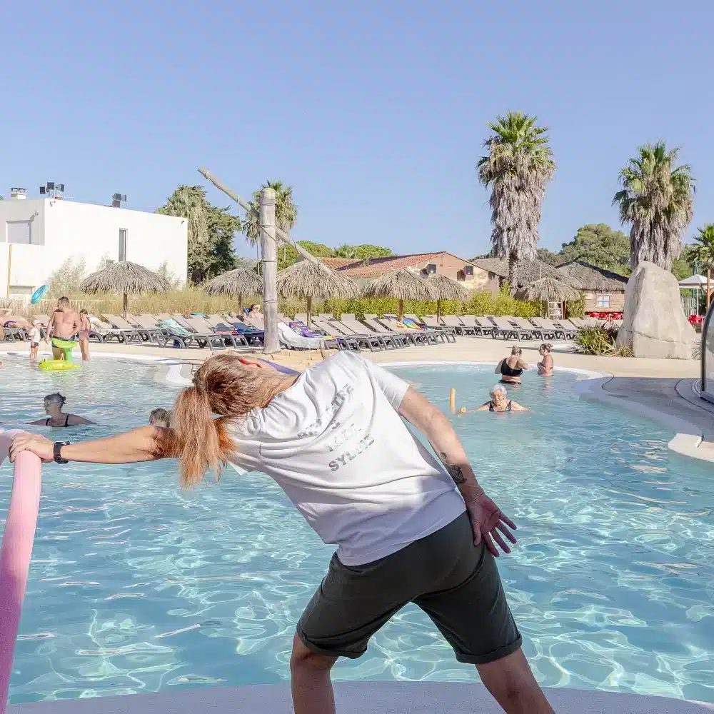 Personnes faisant des exercices dans une piscine extérieure.