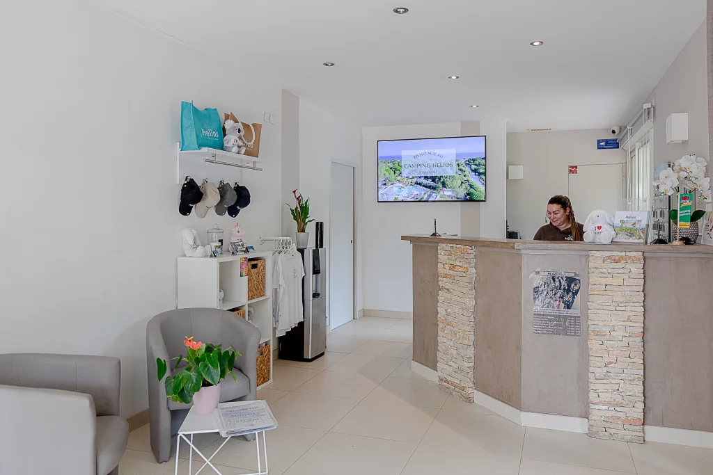 Accueil camping moderne avec réceptionniste souriante.