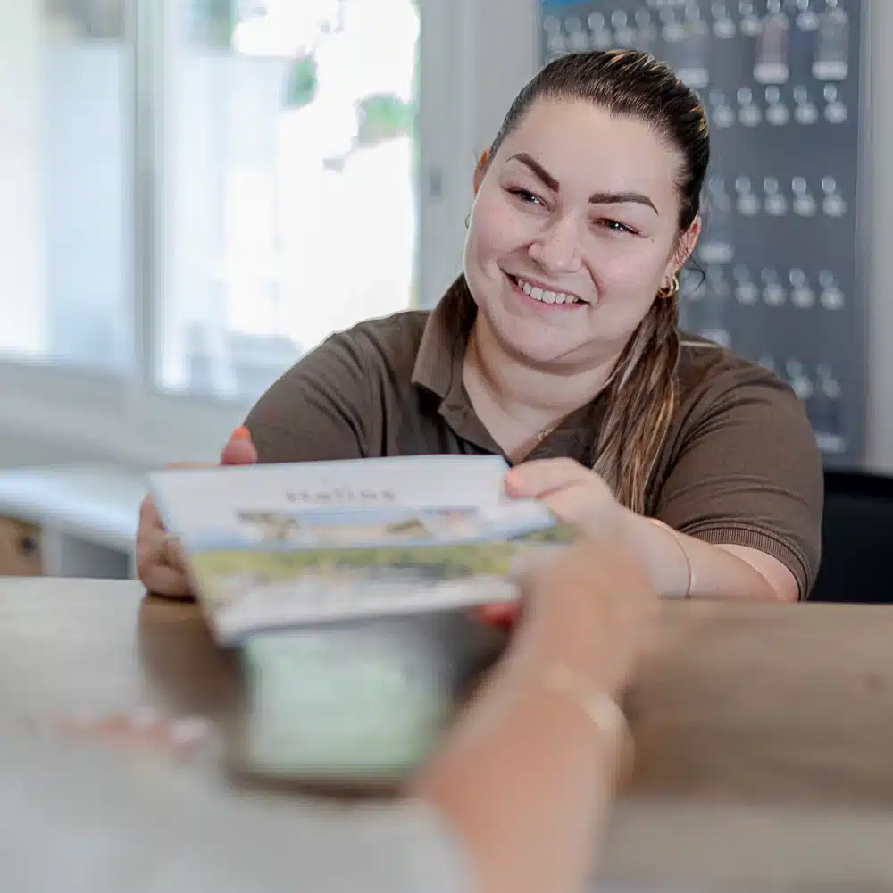 Femme souriante donnant un dépliant.