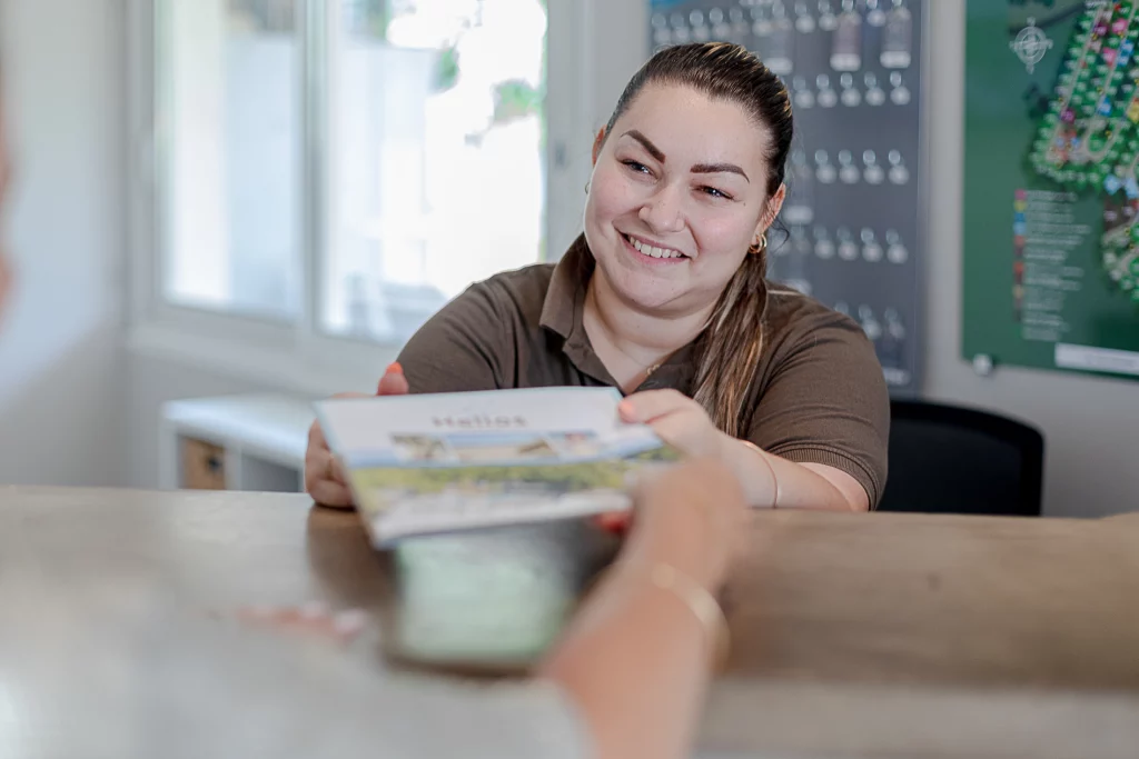 Femme souriante donnant un dépliant.