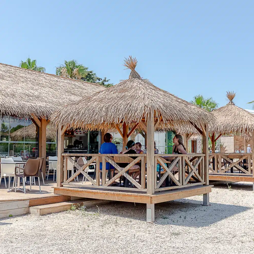 Terrasse extérieure avec paillotes et chaises.