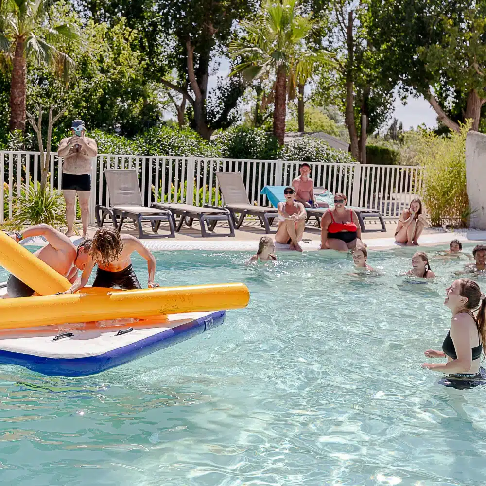 Enfants jouant sur une plateforme flottante en piscine.