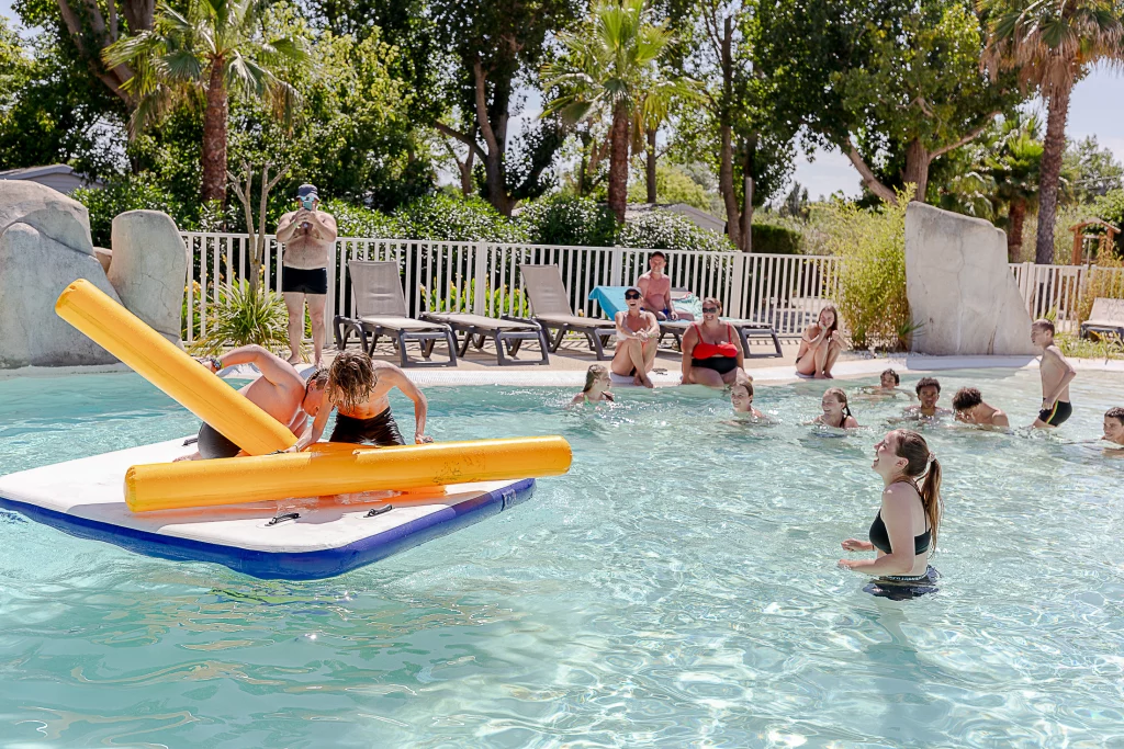 Enfants jouant sur une plateforme flottante en piscine.