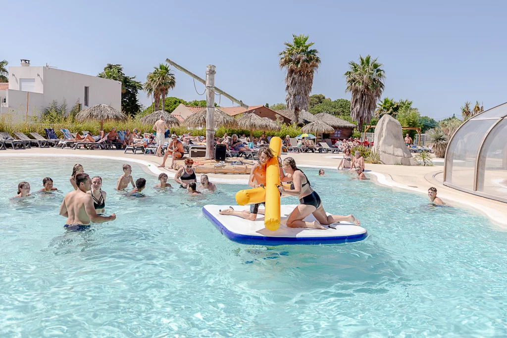 Personnes s'amusant dans une piscine ensoleillée.