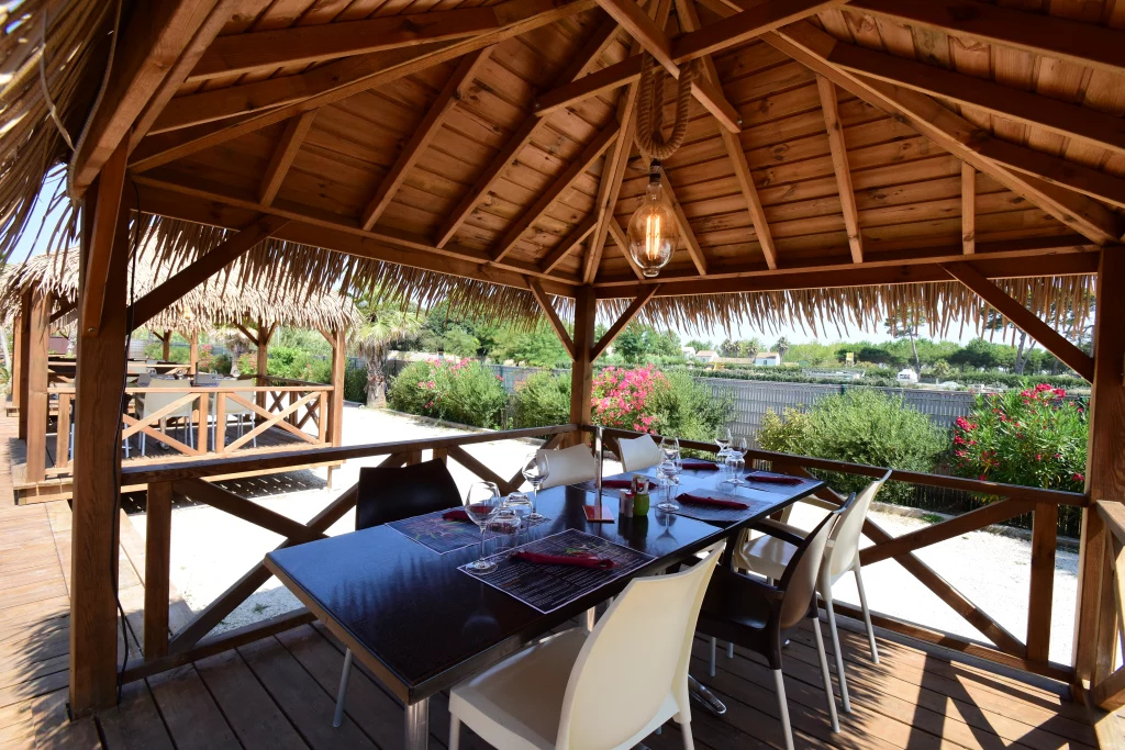 Terrasse extérieure avec tables et chaises sous pergola.