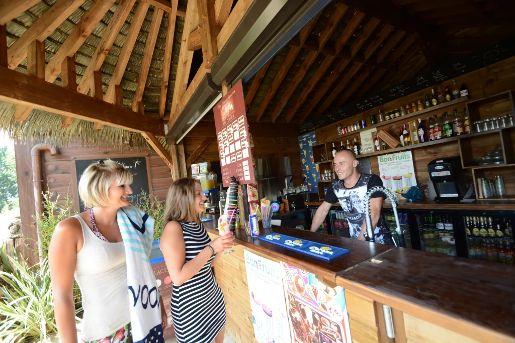 Deux femmes commandant au bar en bois ensoleillé.