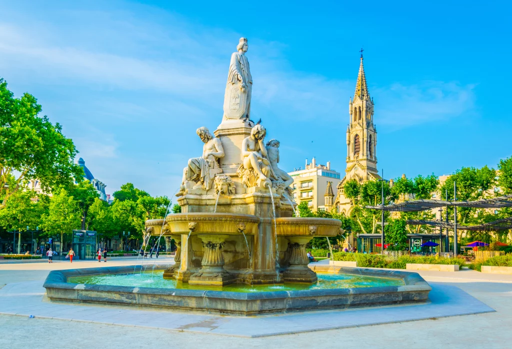 Fontaine avec sculptures dans un parc urbain, ciel bleu.