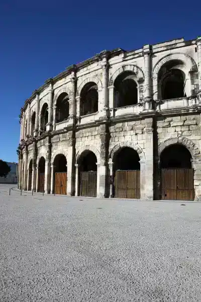 Amphithéâtre romain en pierre sous ciel bleu.