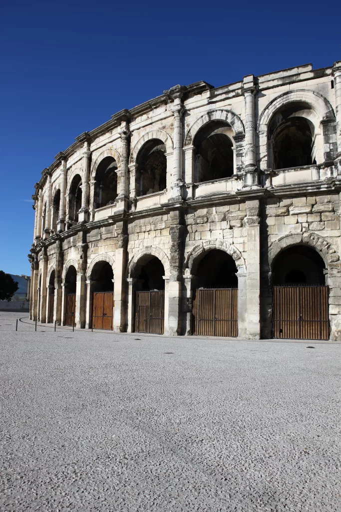 Amphithéâtre romain en pierre sous ciel bleu.