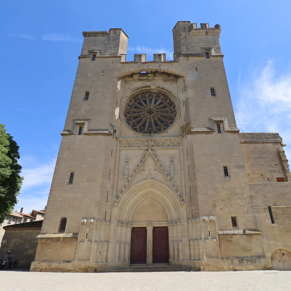 Cathédrale en pierre avec rosace, ciel bleu.