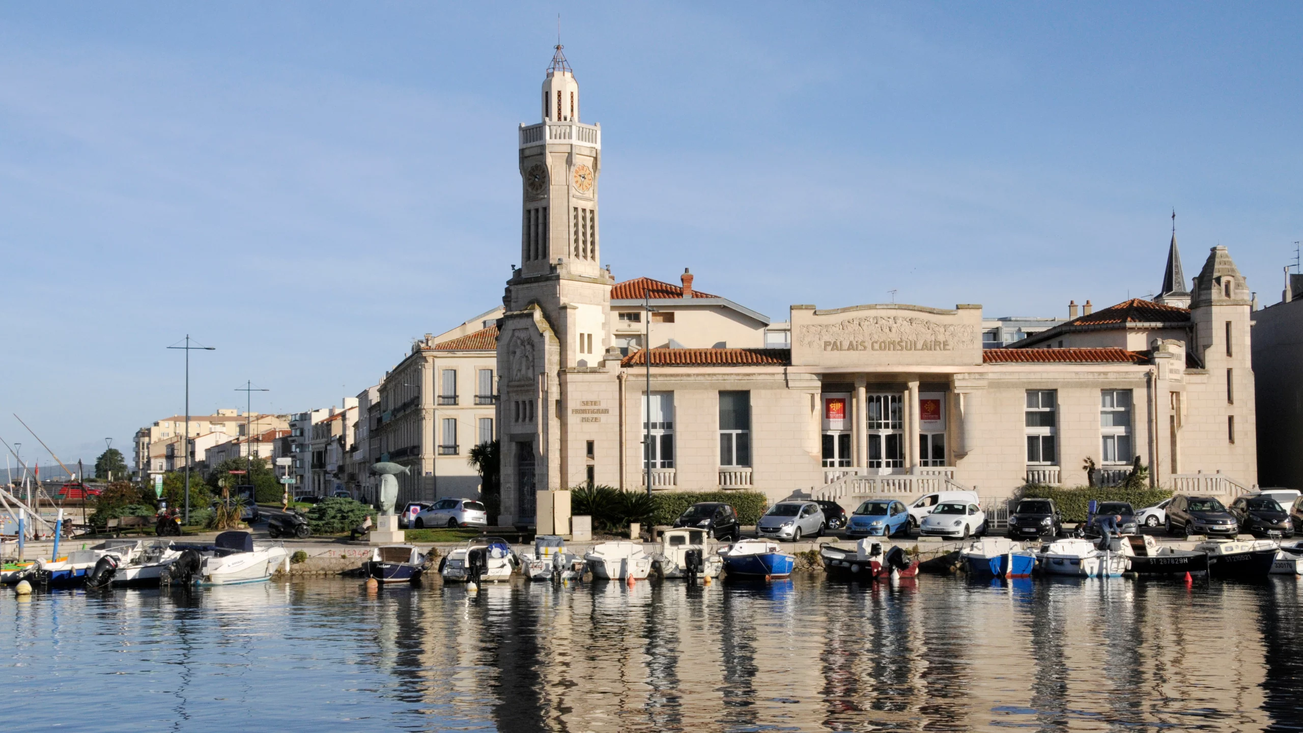 Palais Consulaire devant canal avec bateaux amarrés.