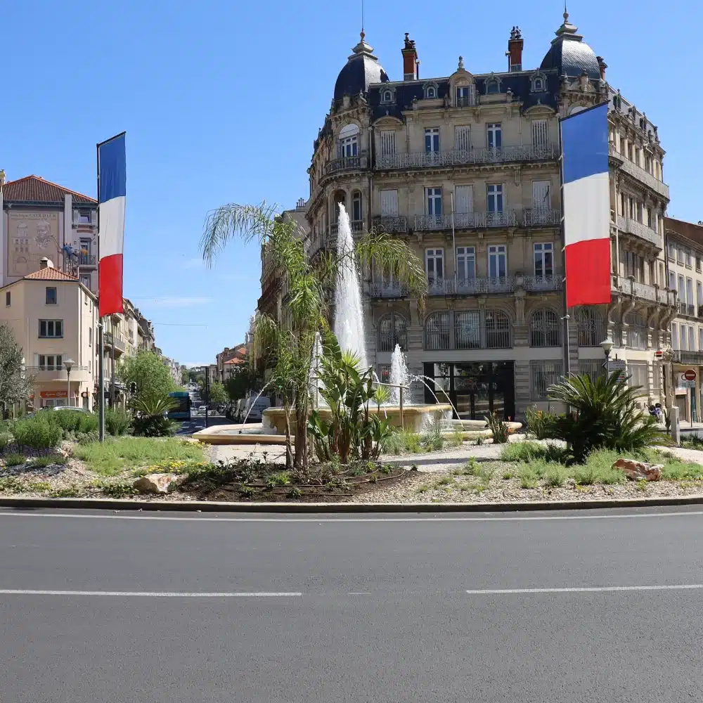 Place avec fontaine et drapeaux français.
