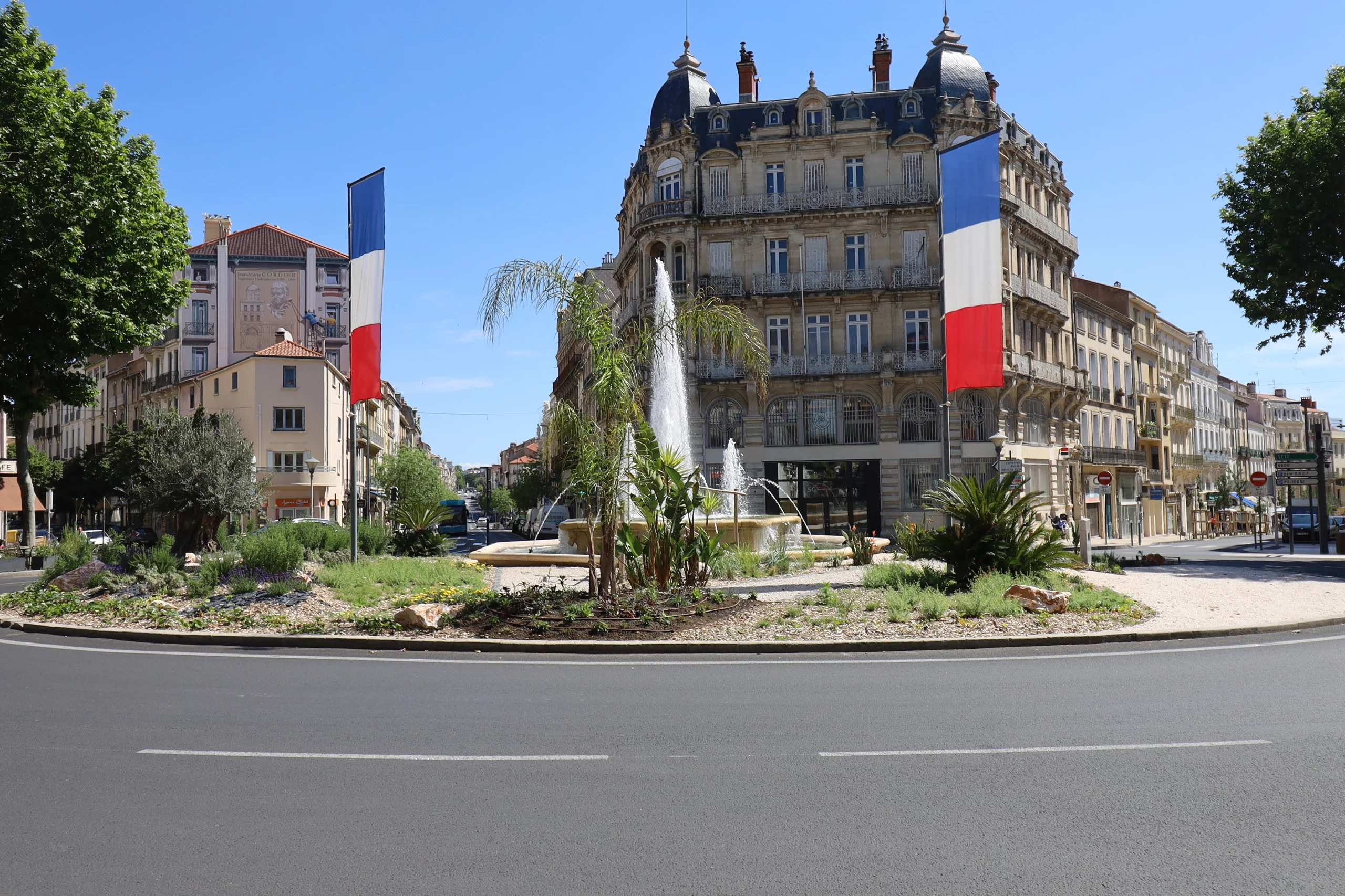 Place avec fontaine et drapeaux français.