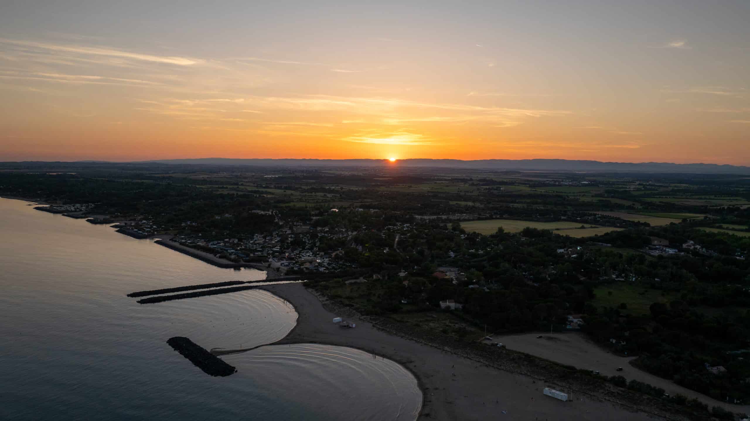 Coucher de soleil sur plage et paysage côtier.